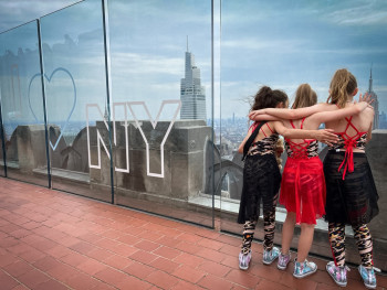 Three girls in dance costumes at top of the rock New York